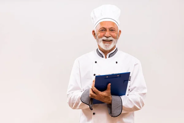 高级厨师持有灰色背景食谱的肖像 — 图库照片