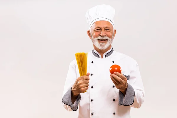 Porträtt Seniorkock Som Håller Tomat Och Spaghetti Grå Bakgrund — Stockfoto