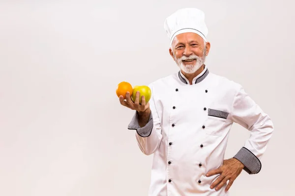 高级厨师拿着水果的形象和灰色背景的思考 — 图库照片