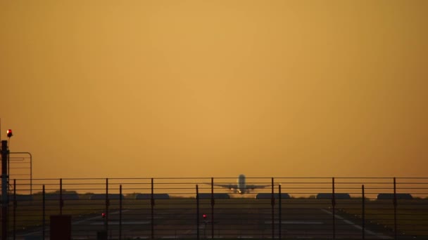 Vliegtuig opstijgen in silhouet tegen een oranje avondrood — Stockvideo