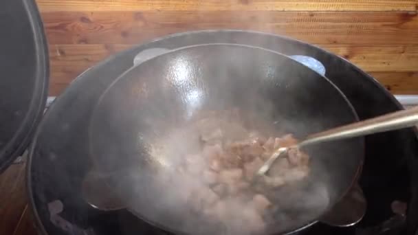 Fritura de carne em um kazan em uma grelha de gás — Vídeo de Stock