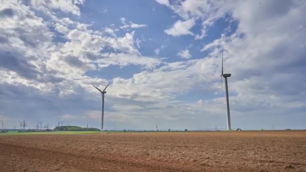 Windgeneratoren und Traktor pflügen das Feld — Stockvideo