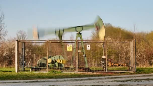 Czas pracy pompy olejowej z pola naftowego o zachodzie słońca w Dolnej Saksonii. Niemcy. — Wideo stockowe