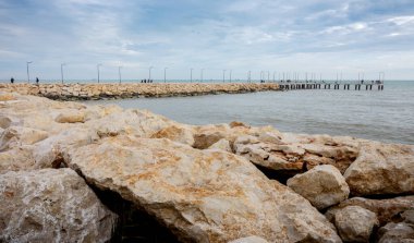 İnsanlar manzaranın tadını çıkarmak için rıhtıma giden kayalar.