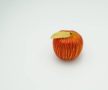 beyaz arkaplanda altın yaprakla süslenmiş portakal elması 