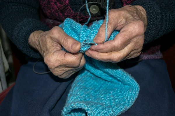 old lady hands crocheting at a sweater