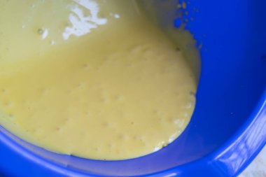 close up of a blue bowl with liquid dough