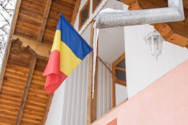romanian flag on a balcony through branches into a winter day