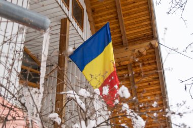 romanian flag on a balcony through branches into a winter day