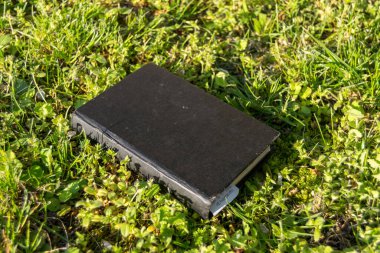 Yeşil çimenler üzerine kapalı siyah kitap