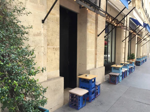 Bar terrace in Paris with tables and chairs made of worn blue soda boxes.
