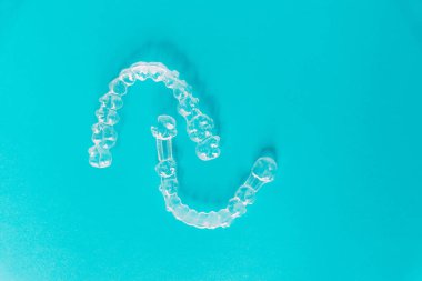 Gökyüzü mavisi arkaplanda kopyalama alanı olan iki saydam diş hizalayıcı örneği.