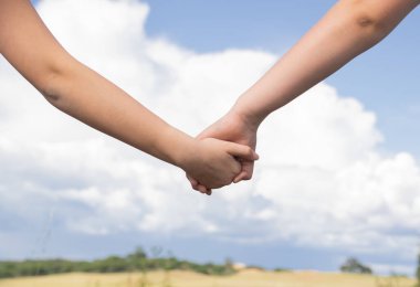 Mavi gökyüzünün arka planında iki kardeş arasında el ele tutuşmak, Aile