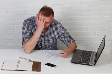 Masada oturan ve bilgisayarda çalışan bir işadamı. Önemli iş görevleri çözdü. O başarılı ve iyi eğitimli. Beyaz bir arka plan üzerinde tek başına.