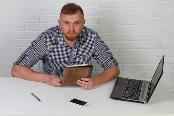 Businessman sitting at the table and working on the computer. It solves important business tasks. He is successful and well-trained. He alone on a white background.