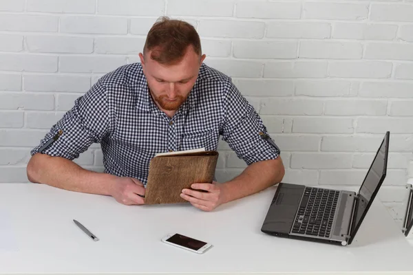 Businessman sitting at the table and working on the computer. It solves important business tasks. He is successful and well-trained. He alone on a white background.