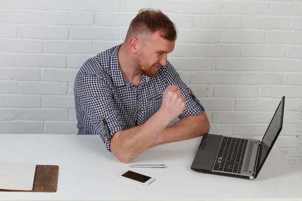 Businessman sitting at the table and working on the computer. It solves important business tasks. He is successful and well-trained. He alone on a white background.