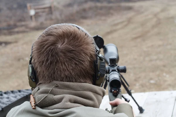 Muž střílí z pušky. Puška střelbu s optickým zaměřovačem venku u muže. — Stock fotografie