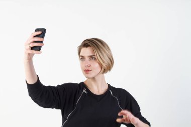 Genç güzel iş kadını beyaz duvara telefonunuzda selfie yapar