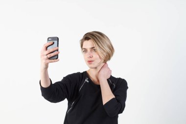 Genç güzel iş kadını beyaz duvara telefonunuzda selfie yapar