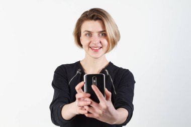 Genç güzel iş kadını beyaz duvara telefonunuzda selfie yapar