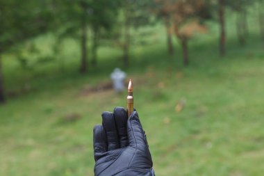 Bir adam bir tüfek ve tabanca kurşunu elinde tutuyor..