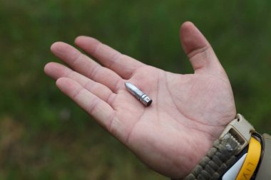 Bir adam bir tüfek ve tabanca kurşunu elinde tutuyor..