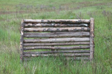 Yeşil çim sahada ahşap bir bariyer duruyor.