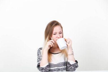 Bir kız kahve içme ve Evet. Beyaz bir arka plan üzerinde bir masada oturuyor.