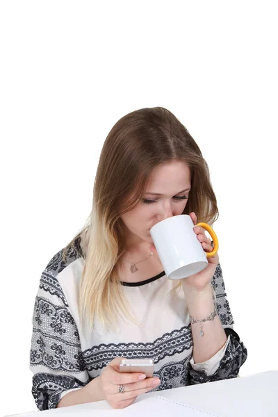 Empresária escrevendo uma mensagem e bebendo café no escritório em uma mesa em um fundo branco . — Fotografia de Stock