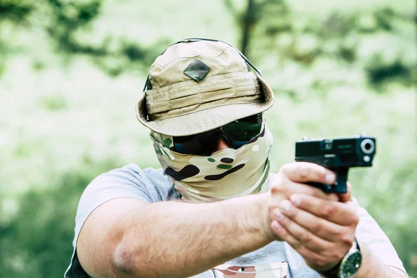 Un hombre dispara una pistola. Él nos mira. —  Fotos de Stock