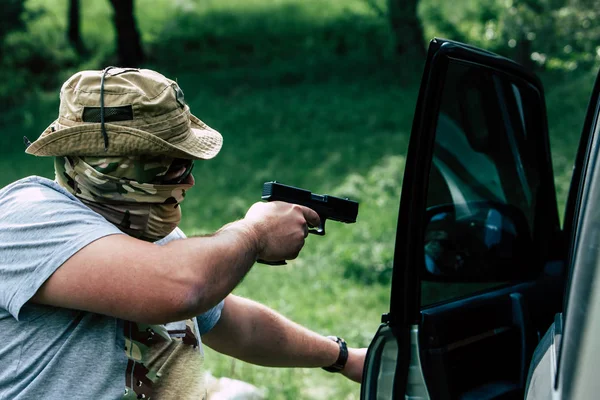 Homem com uma arma abre a porta do carro — Fotografia de Stock