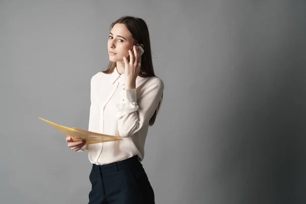 Portret kobieta rozmawia przez telefon. Jeden jest na białym tle na szarym tle — Zdjęcie stockowe