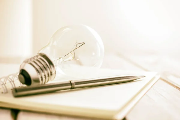 closeup pen on notebook with light bulb, creative writing concept