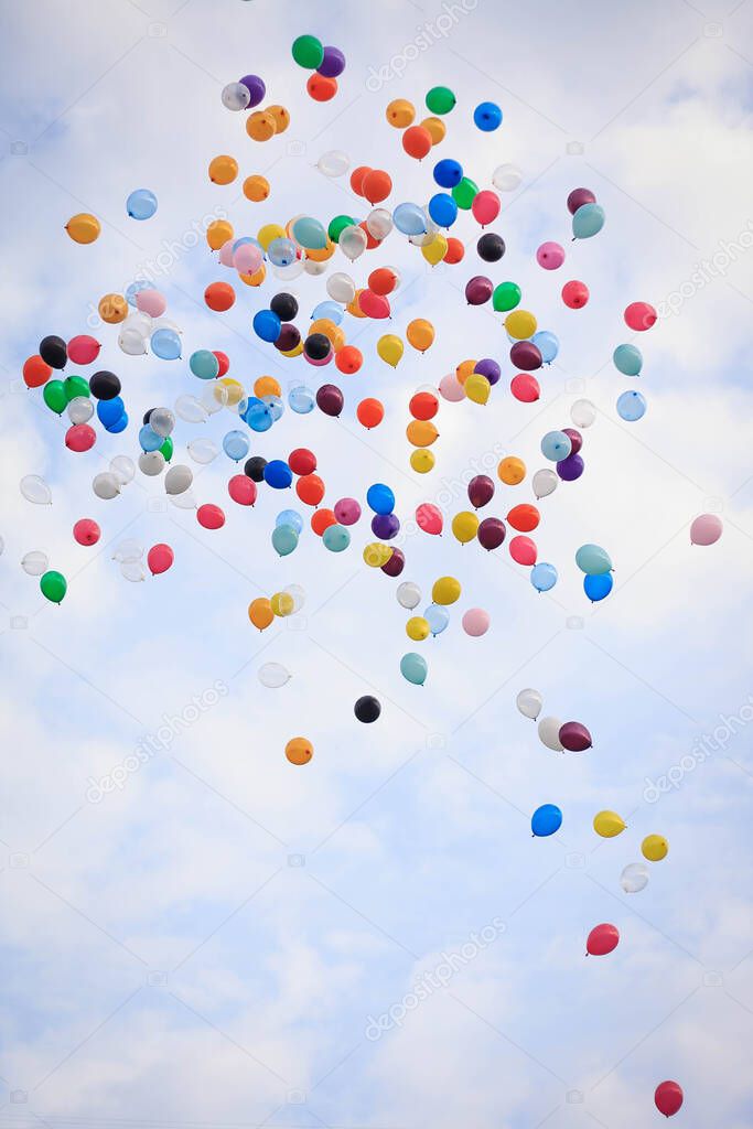 Many multicolored air balloons are flying up into the cloudy sky. Autumn celebration. First September