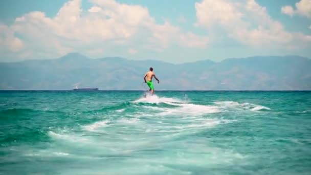 Jovem surfista masculino ativo montando profissionalmente na superfície da água. Exclusivo pranchas de surf elétrico, esporte extremo no mar. Paraíso marinho, emoções de liberdade. Surfista jovem captura ondas, FHD — Vídeo de Stock