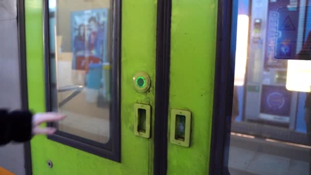 Närbild av flickor hand trycka på grön knapp i tågdörren för att öppna den på stationen. Kvinnlig passagerare väntar på tågets ankomst och dörröppning. Kvinnan går in i tågvagnen och fortsätter — Stockvideo