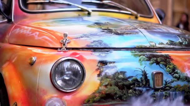 ROME, ITALY - JULY 2019: Mini orange retro car Fiat 500 with amazing colorful graffiti parked on the central street of Rome Via del Corso. Vintage iconic car with unique pattern, historical model of — Stock Video