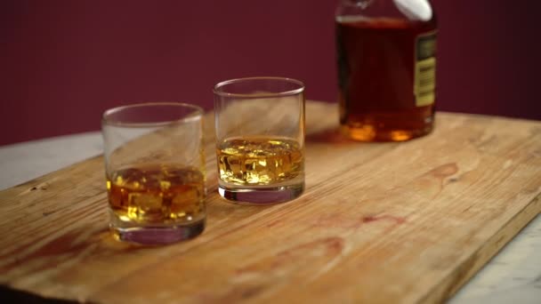 Oude lekkere whisky met ijsblokjes in kristallen glazen op houten bord in lokale bar. Fles whisky voor ontspanning na stress of werk. Oude alcoholische drank — Stockvideo