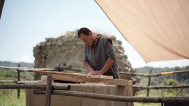 Canale Monterano, İtalya - Mayıs 2018: Ortaçağ erkek esnaf mutfak tezgahında ahşap tavanın içinde taze peynir yapıyor, Monterano 'daki köy pazarında ortaçağ sanatçısı yemeklerini canlandırıyor.