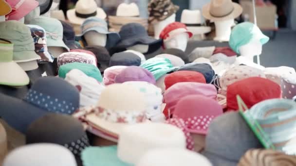 A pile of different types and styles of summer panama hats and caps displayed on local market counter. Trading on flea market, textile production, handmade accessories — Stock Video