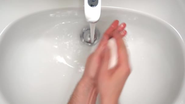 Top view of clean white bathroom faucet with flowing water from tap, man cleaning hands with soap under warm water, disinfectant soap for preventing microbe expansion. Hygiene and skincare, washing — Stock Video