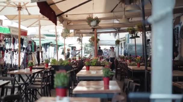 ROMA, ITALIA - LUGLIO 2018: Incredibile ristorante esterno sulla piazza centrale di Roma. Tavoli vuoti in legno decorati con piante fresche fiorite in vasi rossi. Amichevole cameriera sorridente rimanere nesr — Video Stock