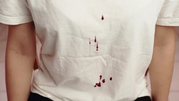Bloed van boven naar beneden laten vallen op een wit T-shirt, moordenaar die zijn slachtoffer langzaam martelt, pijn en lijden. Moordenaar met agressie tegen persoon, discriminatie en tirannie. Vechten tussen mensen — Stockvideo