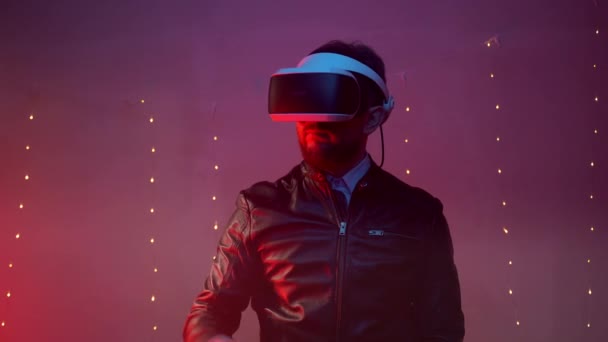 Profesjonalny inżynier noszący słuchawki wirtualnej rzeczywistości w małym, czerwonym oświetlonym pomieszczeniu, człowiek gestykulujący ręką i pokazujący obracanie stron. Cyfrowy ekran w rozszerzonej rzeczywistości — Wideo stockowe