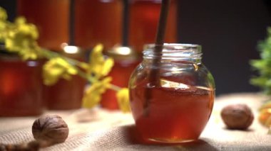Kırsal üretimle dolu bal kavanozları, ahşap kaplamayla karıştırılmış altın sıvı bal. Sopadan damlayan saf doğal bir ürün, vitamin dolu sağlıklı bir malzeme. Organik sarı bal