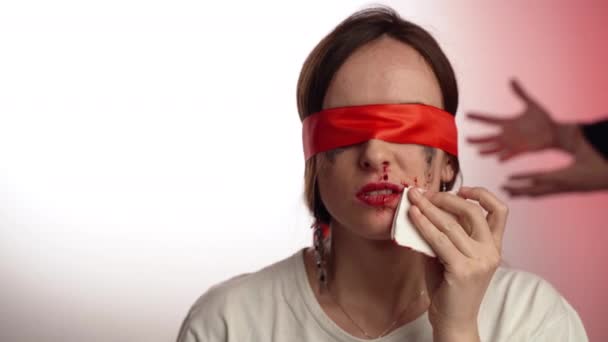 Violencia y agresión contra las mujeres en la sociedad moderna, mujer sangrienta con los ojos cerrados quitando la sangre que fluye de la nariz y los labios con toalla de papel. hombre agresivo en el fondo, estrechando las manos y — Vídeos de Stock