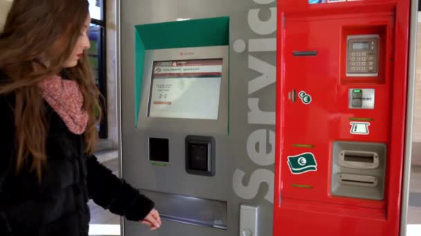 ROME, ITALIEN - JANUARI 3, 2020: Kvinnlig passagerare väntar på två biljetter nära den automatiska biljettautomaten på tågstationen i Rom, flicka genomför köp transaktioner och tar bort biljetter — Stockvideo