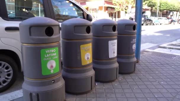 ローマの路上の灰色のプラスチックごみ容器、さらにリサイクルのためのガラス、プラスチック、漫画や有機性廃棄物を分類するための特別な兆候を持つゴミ箱。イタリアの生態学的問題 — ストック動画