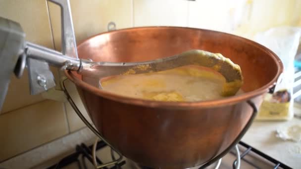 Preparação rústica tradicional de polenta amarela em caldeirão de cobre com mexendo batedor de metal, farinha de milho misturada com água fervente, mingau de milho quente é um prato típico do norte da Itália. Italiano — Vídeo de Stock